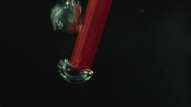 air pressure is coming through ending of red plastic drinking straw under water, water blister shot at HD 100p.