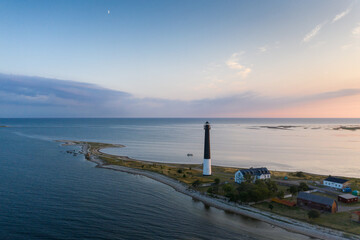 Aerial view over sunset colored seascape with the beautiful clouds and rising moon over long spit  with the historic lighthouse and visitor center in Sõrve Säär, Saaremaa isl., Estonia