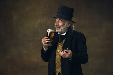 Elderly gray-haired man, gentleman, aristocrat or actor drinking beer isolated on dark vintage...
