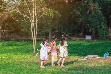 Naklejka na ściany i meble Asian girls and friends playing together on lawn through green garden. Happiness girl friends having fun on field among trees and green grass. Happy friends spending time outside in green nature.