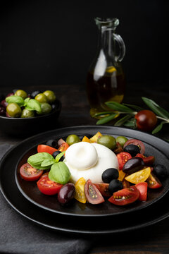 Italian fresh burrata cheese with tomatoes and olives. A healthy diet lunch or dinner. Caprese salad with mozzarella tomatoes and basil