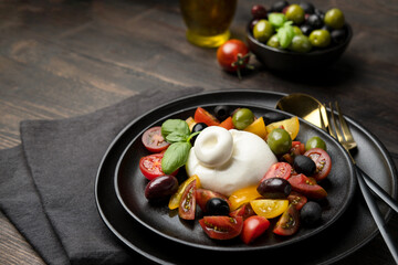 Italian fresh burrata cheese with tomatoes and olives. A healthy diet lunch or dinner. Caprese salad with mozzarella tomatoes and basil