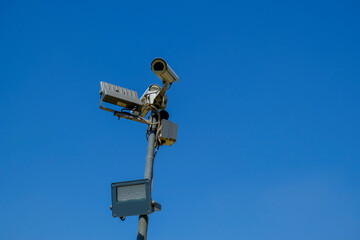 cctv security camera close-up with a lamp on sun battery across blue sky . Security system