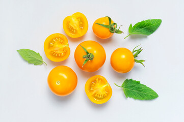 Ripe fresh yellow orange tomatoes with green tails on light gray background flat lay top view. Cherry tomatoes. Vegetables, healthy vegan organic food, harvest concept tomatoes pattern layout cooking