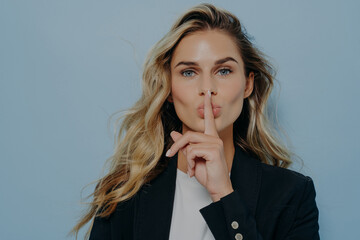 Blonde woman making shush gesture with her hand - obrazy, fototapety, plakaty