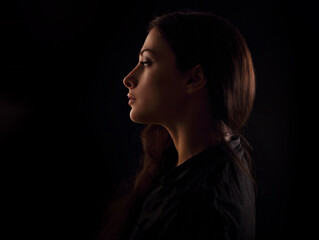 Beautiful serious concentration intelligence business woman in darkness with thinking look in the future on black background. portrait in dark shadow low key. Art. Profile - Powered by Adobe