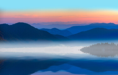 Fototapeta na wymiar Beautiful landscape with high blue mountains with illuminated peaks, and mountain lake reflection