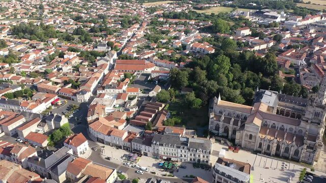 View from drone of houses and ancient Roman Catholic Cathedral of Lucon town at summer day, France