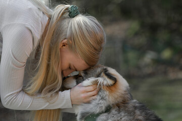 A blonde woman cuddling a Finnish Lapphund dog