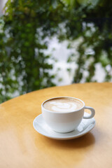 Cup of coffee with latte art on a wooden table in a cafe.