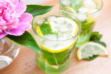 Lemonade drink or mojito cocktail and peony flowers, summer drink with mint and lemon and ice