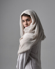 Full length portrait of young woman wearing classical white gown and a head covering veil in...