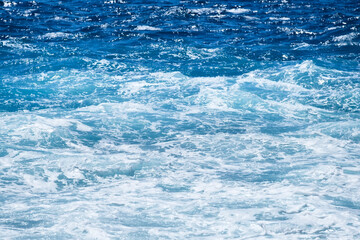 Waves and blue water as a background. View at the ocean surface. Natural summer seascape. Water background. Abstract blue ocean background.