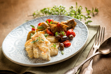 cooked cod with artichoke tomatoes olives capers and herbes