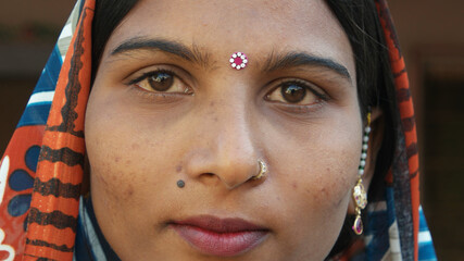 Portrait of a young Indian female with a colorful kerchief, earrings and a nose piercing