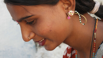 Portrait of a young Indian female with earrings and a nose piercing looking down with a cute smile