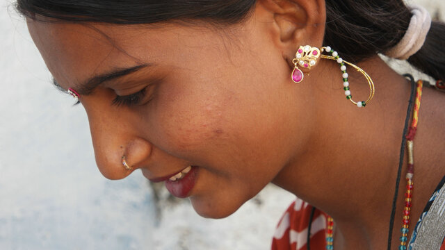 Portrait Of A Young Indian Female With Earrings And A Nose Piercing Looking Down With A Cute Smile