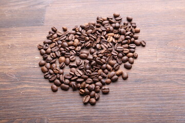 Black coffee grains lie on a brown wooden table, background image