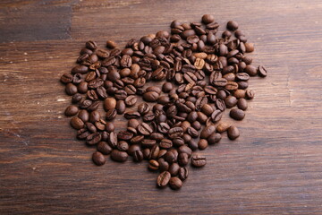 Black coffee grains lie on a brown wooden table, background image