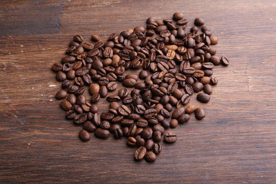Black coffee grains lie on a brown wooden table, background image