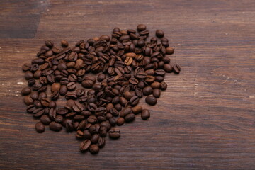 Black coffee grains lie on a brown wooden table, background image