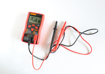 Digital multimeter in red case with probes and backlit display.