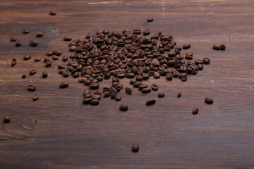 Black coffee grains lie on a brown wooden table, background image