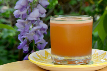 Vodka based cocktail with ice and wisteria flower background