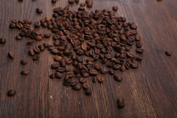 Black coffee grains lie on a brown wooden table, background image