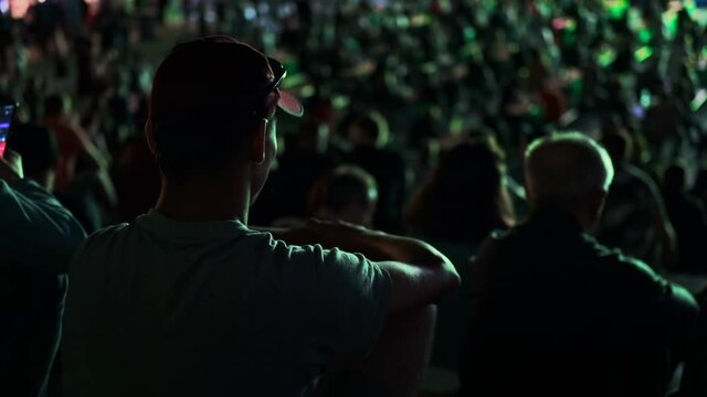Sitting people watching football in a public place at night