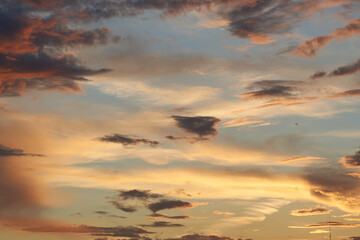 Beautiful evening blue sky at sunset with flaming bright light clouds. A warm summer evening at sunset. Bright sunset.
