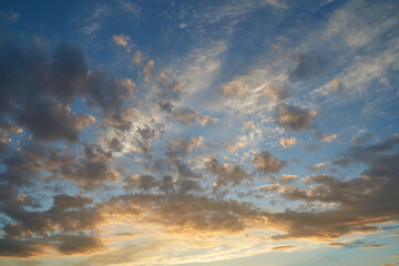 Obraz premium Beautiful evening blue sky at sunset with flaming bright light clouds. A warm summer evening at sunset. Bright sunset.