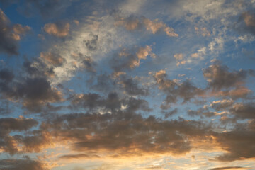Beautiful evening blue sky at sunset with flaming bright light clouds. A warm summer evening at sunset. Bright sunset.