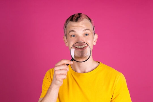 European Handsome Young Man In Yellow T Shirt On Pink Background Playful With  Magnifier, Bright Portrait, Pink Hair