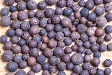 Black balls of fresh spices on a wooden board. Flatlay photo