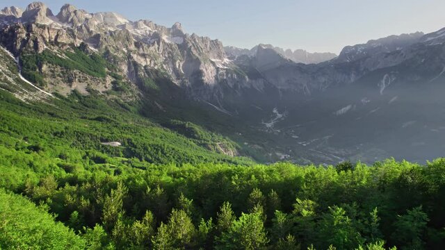 Theth National Park, Albania. Aerial view of albanian alps at sunrise. Flying over green trees overlooking the village of Thethi and majestic mountains - The Accursed Mountains in Albania Prokletije
