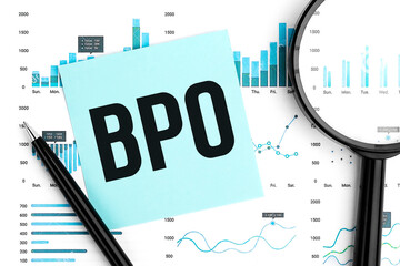 Text BPO Business Process Outsourcing on blue sticker, magnifier, pen, graphs. Business flat lay.