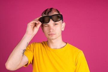 European handsome young man in yellow t shirt on pink background with 3 d cinema glasses