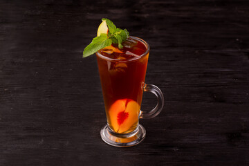 peach tea with pieces of peach, ice and mint