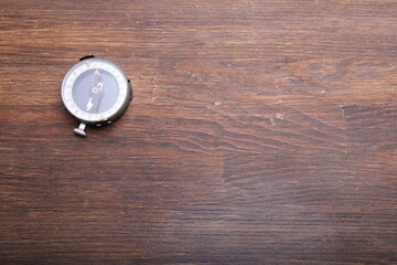 Old compass on brown wooden table background.