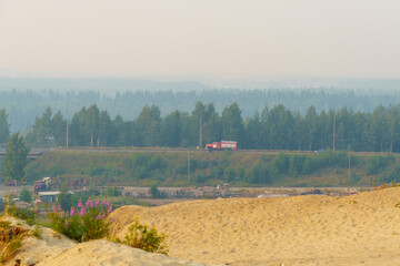 Fire truck hurries along a country road covered with smog from forest fires