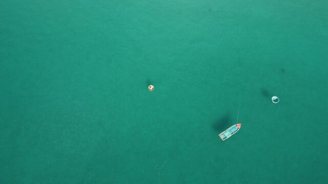 Aerial view. A man is moving in the traditional round boat in the tranquil sea. A colorful fishing boat. Top-down drone shot. Tracking shot of a fisherman.