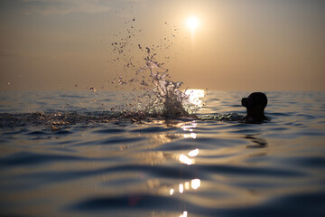 Młodzi przyjaciele kąpią się w morzu o zachodzie słońca. Sepia, backlight, silhouette. - obrazy, fototapety, plakaty