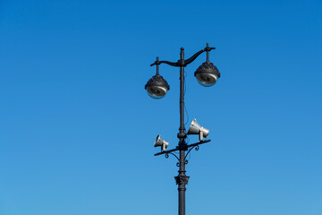 Fototapeta na wymiar Vintage metal lampposts with street lamps and spotlights on blue sky background