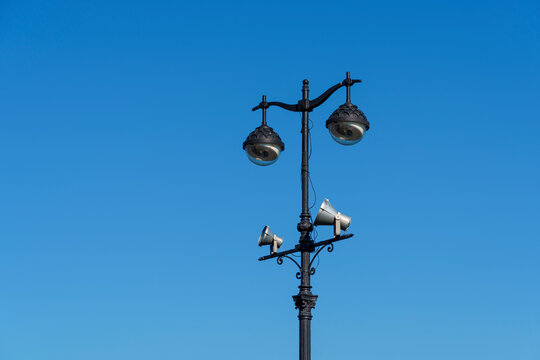 Vintage metal lampposts with street lamps and spotlights on blue sky background