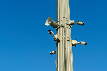 Fototapeta na wymiar CCTV security cameras and outdoor loudspeaker on clear blue sky background