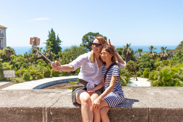 Happy family mother and her adorable little daughter on summer vacation taking selfie with smartphone