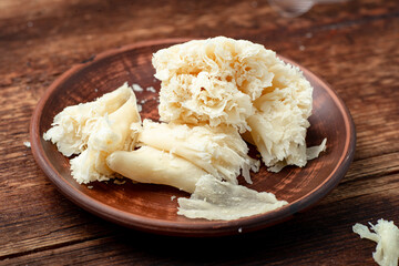 Hard cheese sliced chips on a clay plate on a wooden background.