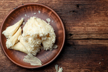 Hard cheese sliced chips on a clay plate on a wooden background.