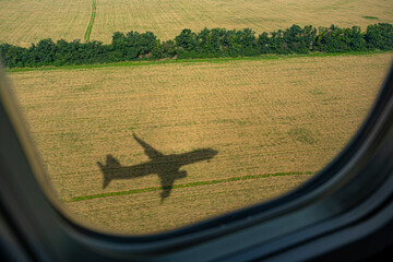 Plane. View from the airplane window. The shadow of an airplane on a yellow field of sunflowers....